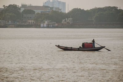 Man rowing boat on river in city