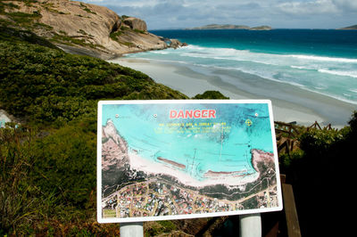 Information sign on rock by sea against sky