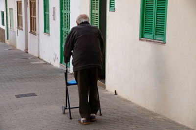 Rear view of pensioner walking on footpath