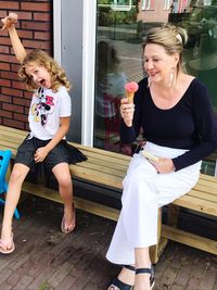 Full length of happy girl sitting outdoors