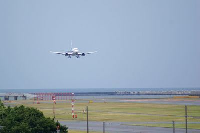 Airplane flying over runway against clear blue sky