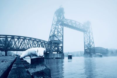 Bridge over river against clear sky during winter