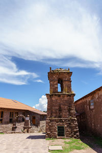 Low angle view of bell tower amidst houses against sky