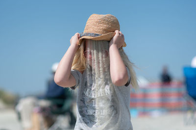 Playful girl pouring sand on head at beach