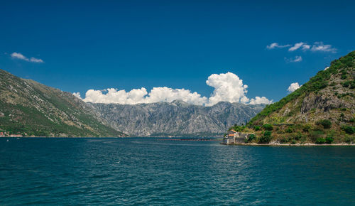 Scenic view of sea and mountains against blue sky