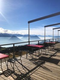 Empty chairs and table by sea against sky