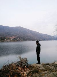 Rear view of woman standing at lakeshore