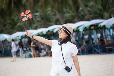Woman holding umbrella while standing on beach