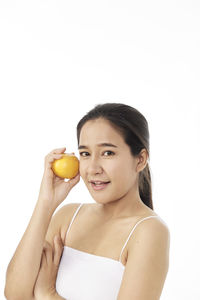 Portrait of young woman holding apple against white background