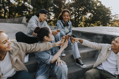 Teenagers sitting in skate park and give each other fist bump