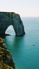 Rock formation in sea against clear sky