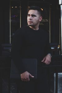 Close-up of man with file standing against window