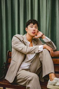 Young man looking away while sitting on chair