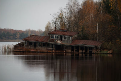 House by lake against sky