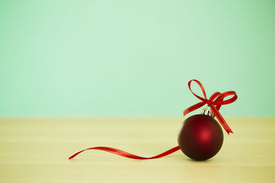 Close-up of red christmas decoration on table against wall