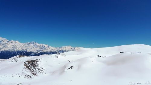 Scenic view of snowcapped mountains against clear blue sky