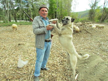 Full length of man holding dog on field