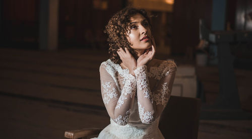 Sensuous woman in wedding dress sitting with head in hands at home