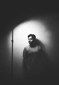Portrait of young man standing against wall