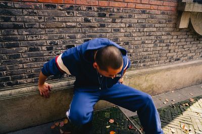 Rear view of man sitting against wall