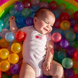 High angle view of smiling cute baby girl lying in ball pool