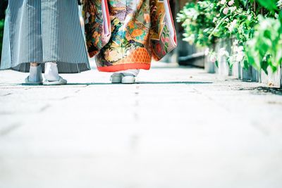 Low section of woman standing on footpath