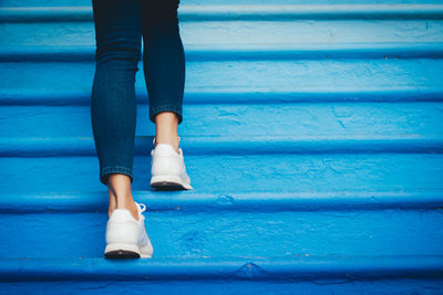 Low section of woman walking on blue steps