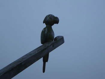 Low angle view of bird perching against sky