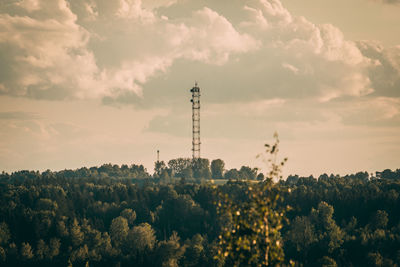 Panoramic view of communications tower and trees against sky