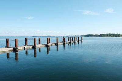 Wooden posts in sea against sky