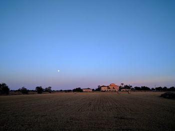 Scenic view of field against clear blue sky at night