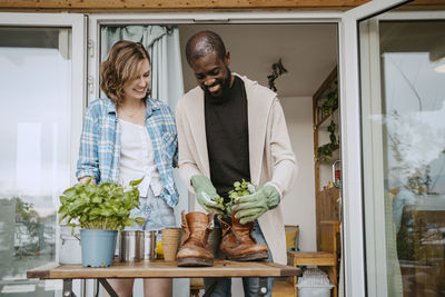 Happy multiracial couple doing gardening outside house