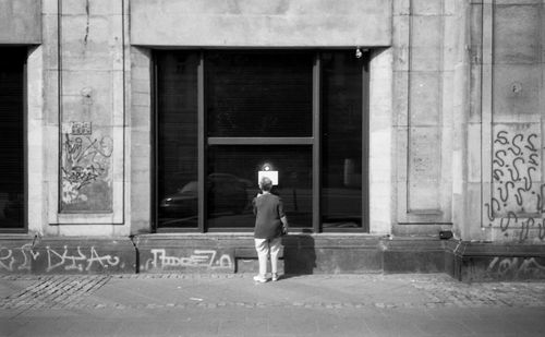 Rear view of man walking on footpath against building