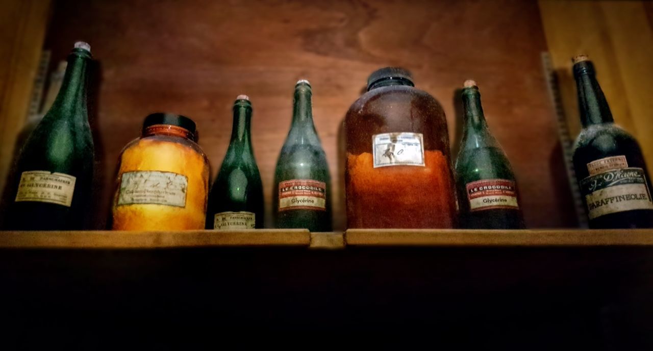 bottle, container, still life, indoors, shelf, drink, variation, food and drink, no people, refreshment, alcohol, side by side, wood - material, choice, large group of objects, text, in a row, arrangement, label, wine, order