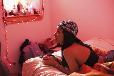 Woman looking away while sitting on bed at home