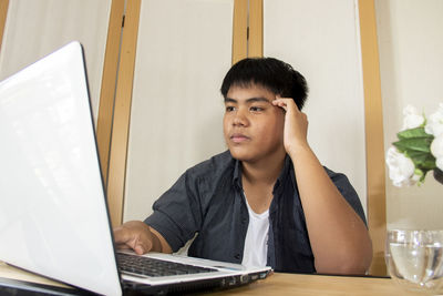 Portrait of young man using phone while sitting on table