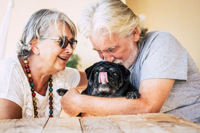 Senior man with woman embracing dog while sitting at home