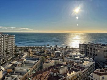 High angle view of sea by buildings against sky during sunset