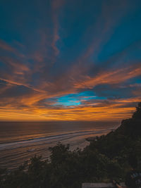 Scenic view of sea against dramatic sky during sunset