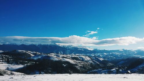 Scenic view of snowcapped mountains against cloudy sky