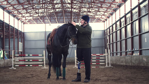 A disabled man jockey strokes a muzzle of a thoroughbred man has prosthesis instead of his right leg