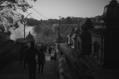 Rear view of men standing on street against sky