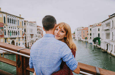 Portrait of friends standing on canal against buildings