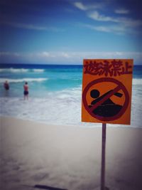 Information sign on beach against sky