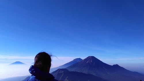 Woman on snowcapped mountain against blue sky