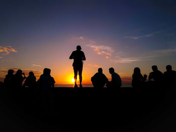 Silhouette people on beach against sky during sunset