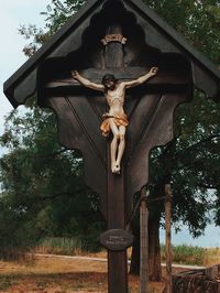 Low angle view of cross statue against trees