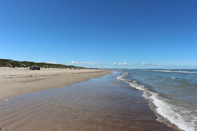 Scenic view of beach against clear blue sky