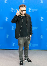 Full length of young man standing against blue wall