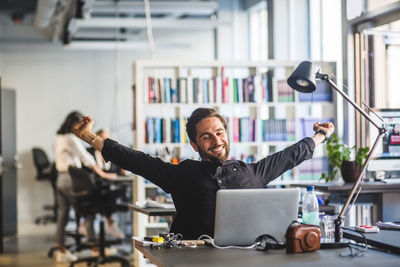 Businessman sitting with arms outstretched at desk in office